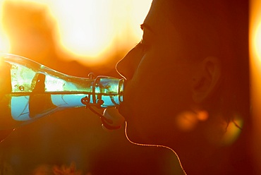 Young attractive girl drinking water at sunset