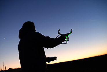 Young man flying Phantom Drone outdoors at sunset