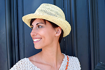 Attractive young woman with summer style and straw hat in street