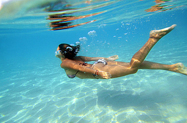 Young woman swims underwater in the beautiful waters of Menorca, Spain