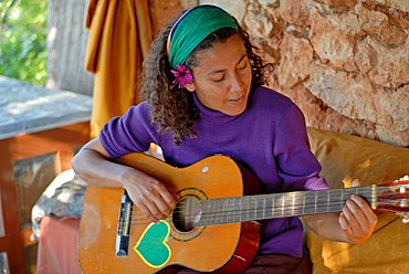 Attractive young brazilian woman plays the guitar at Greenheart?s La Casita Verde, Ibiza