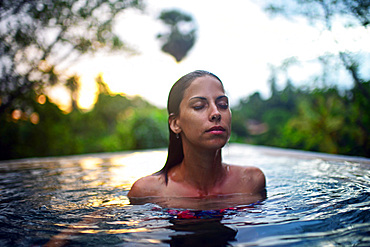 Young attractive woman enjoying a bath in the infinity edge swimming pool at The Dutch House, Galle, Sri Lanka