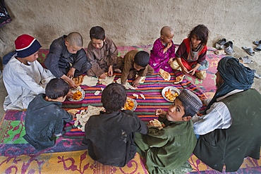 Afghan family having lunch in their mud house