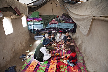 Afghan family having lunch in their mud house