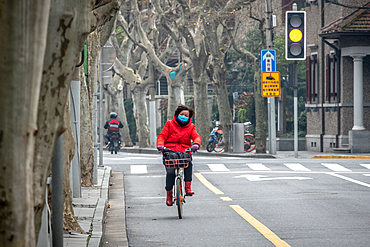 Shanghai, China, 27th Jan 2020, A woman riding her bicycle wearing a mask on a nearly empty road to avoid catching the Coronavirus