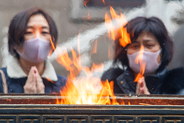 Shanghai, China, 23rd Jan 2020, Two women wearing masks pray next to fire