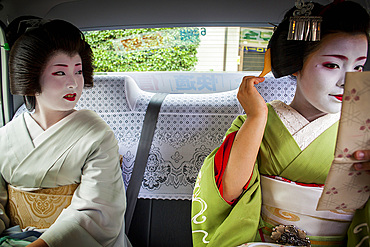 Fukuyu,geisha and Fukukimi,'maiko' (geisha apprentice)in taxi going to work.Geisha's distric of Miyagawacho.Kyoto. Kansai, Japan.