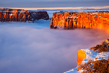 First light at sunrise on the Wingate cliffs of Junction Butte & Grandview Point with a sea of clouds below. Canyonlands NP, Utah. A winter temperature inversion produce this weather phenomenon.