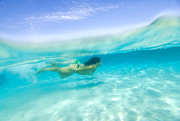 Above and below young girls diving in the clear waters of Formentera, Balearic Islands, Spain