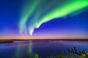 An arc of Northern Lights appears in the evening twilight over Prelude Lake near Yellowknife, NWT, on September 9, 2019. The Big Dipper is at left. Capella is at right.