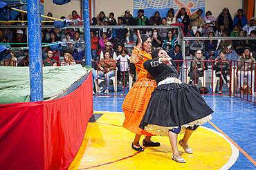 Lucha Libre. Combat between Dina with orange dress and Julieta, cholitas females wrestlers ,Sports center La Ceja, El Alto, La Paz, Bolivia