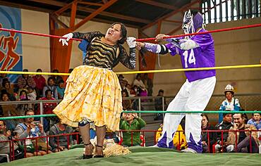 Lucha Libre. Male fighter stretch the hair of cholita Julieta, wrestlers in combat, Sports center La Ceja, El Alto, La Paz, Bolivia