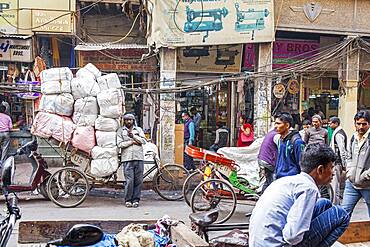 Carrier, resting and chatting through phone, in Nai Sarak street, near Chandni Chowk, Old Delhi, India