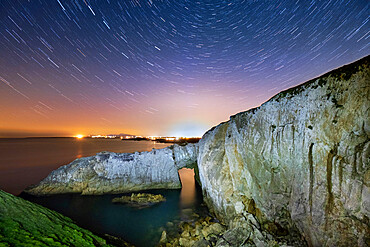 Star trails and night sky over Bwa Gwyn or the White Arch, near Rhoscolyn, Anglesey, North Wales, United Kingdom, Europe