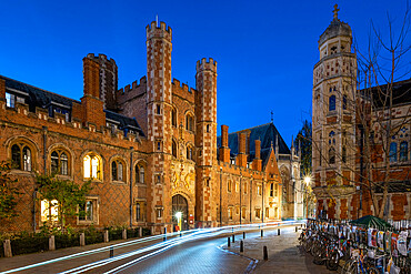 Bicycle light trails passing the Great Gate at St Johns College at night, Trinity Street Cambridge, Cambridgeshire, England, UK