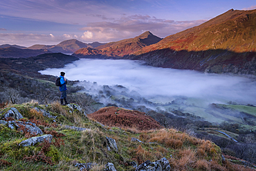 Walker looking out over the peak of Yr Aran and a fog filled Nant Gwynant Valley, Nant Gwynant, Eryri, Snowdonia National Park, North Wales, United Kingdom, Europe