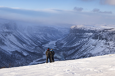 Couple in Snowsuits looking out over the Alta Canyon and Alta River from the Finnmark Plateau in winter, Finnmark Plateau, near Alta, Norway, Arctic Circle, Scandinavia, Europe