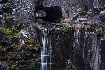 Waterfall falling from a Slate Cavern tunnel entrance, Dinorwig or Dinorwic Quarry, Eryri or Snowdonia National Park, North Wales, UK