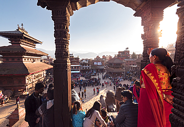 Locals in colorful clothes enjoy a sunny festival day around the temples and architecture of Bhaktapur, Nepal, Asia