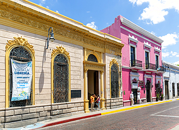 Brightly painted traditional Spanish colonial style buildings in city centre including the yellow Public Library, Merida, Yucatan State, Mexico, North America