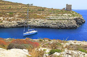 Yacht and watchtower at entrance to Mgarr ix-Xini coastal inlet, island of Gozo, Malta, Mediterranean, Europe