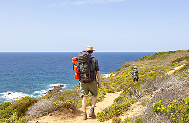 Two people walking the cliff top coastal long distance footpath trail, The Fisherman's Walk (Ruta Vicentina), near Odeceixe, Algarve, Portugal, Europe