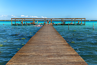 People sitting on woooden jetty pier by waterside, Lake Bacalar, Bacalar, Quintana Roo, Yucatan Peninsula, Mexico, North America