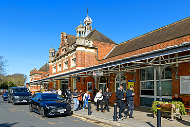People and taxis outside Colchester North mainline railway station building, Essex, England, UK