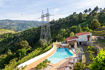 Electricity pylons crossing countryside over swimming pool, Tresouras, near Mesão Frio, River Douro valley, Portugal, Europe
