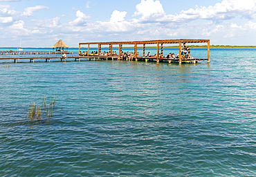 People sitting on woooden jetty pier by waterside, Lake Bacalar, Bacalar, Quintana Roo, Yucatan Peninsula, Mexico, North America