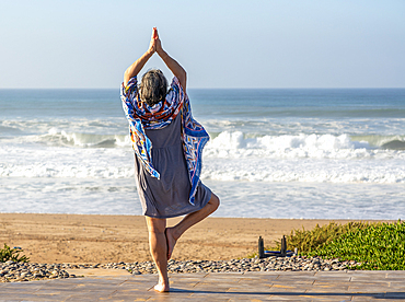 Woman performing yoga Tree pose, Vrikshasanayoga, Atlantic Ocean, Morocco, North Africa, Africa