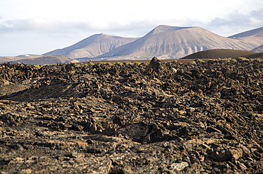 Volcanic landscape of solidified lava flows and distant cone volcanoes, near Yaiza, Lanzarote, Canary Islands, Spain, Atlantic, Europe