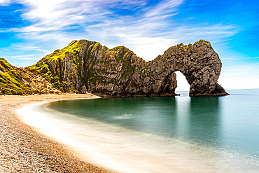 Scenic view of a natural arch on a coastline with a sandy beach and clear blue sky at Durdle Door, Jurassic Coast, UNESCO World Heritage Site, Dorset, England, United Kingdom, Europe