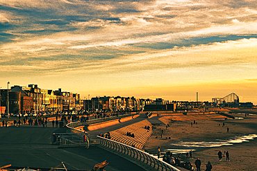 Golden sunset over a bustling beach promenade with silhouetted people and modern buildings in Blackpool, England