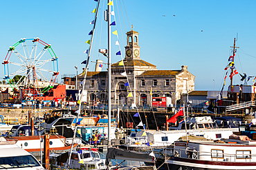 Bustling harbor with boats docked, historic building in the background, and a Ferris wheel under a clear blue sky , Hastings, East Sussex, England, United Kingdom, Europe