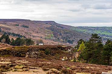 Scenic view of a rugged landscape with rolling hills, rocky outcrops, and sparse vegetation under a cloudy sky in Ilkley, North Yorkshire, England, United Kingdom, Europe