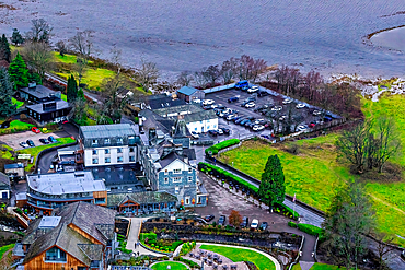 Aerial view of a lakeside hotel with buildings and parking area surrounded by greenery in the Lake District, Cumbria, England, United Kingdom, Europe