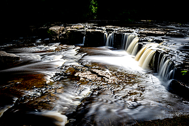 Long exposure of a serene waterfall cascading over rocky ledges, North Yorkshire, England, United Kingdom, Europe