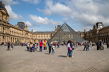 Tourists at the Louvre Museum courtyard with iconic glass pyramid and historic palace, Paris, France, Europe