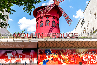 Iconic red windmill of the Moulin Rouge cabaret under blue sky, Paris, France, Europe