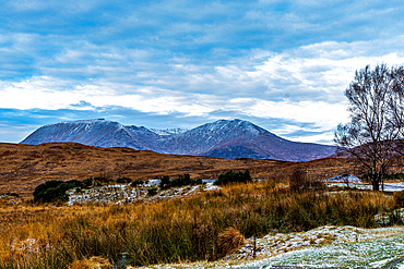 Serene landscape with frost-covered grass, a tranquil lake, and distant snow-capped mountains under a cloudy sky, Scotland, United Kingdom, Europe