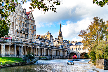 Picturesque view of historic city with River Avon, boat, and classic architecture under a cloudy sky, Bath, Somerset, England, United Kingdom, Europe