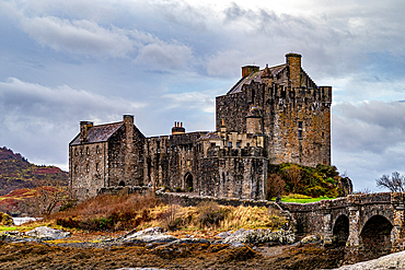 Majestic medieval castle with stone bridge over a river, surrounded by wild nature under a cloudy sky, Eilean Donan, Dornie, Scotland, United Kingdom, Europe