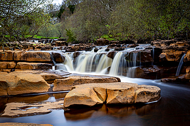 Serene waterfall cascading over rocks with lush greenery in the background, showcasing nature's tranquility, North Yorkshire, England, United Kingdom, Europe