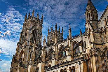 Gothic cathedral tower against a dramatic cloudy sky, showcasing intricate architectural details and spires, ideal for historical or religious themes in York, North Yorkshire, England.