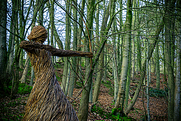 Straw sculpture of a humanoid figure in a forest, with arms outstretched amidst bare trees, Skipton, Yorkshire, England, United Kingdom, Europe