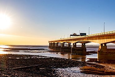 Sunset view of the Prince of Wales Bridge, the Second Severn Crossing, M4 motorway over the River Severn, reflections on water, clear skies, and warm sunlight, between England and Wales, United Kingdom, Europe