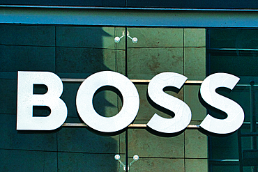 Close-up of 'BOSS' sign in white lettering on a green tiled wall with glass panels in Manchester, UK.