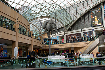Interior view of a multi-level shopping mall with a metal horse sculpture and various shops and people in Leeds, UK.