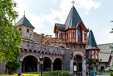 Exterior view of a building with stone facade, towers, arches, and a sign reading 'Blanche Neige et Sept Nains. at Disneyland Paris.